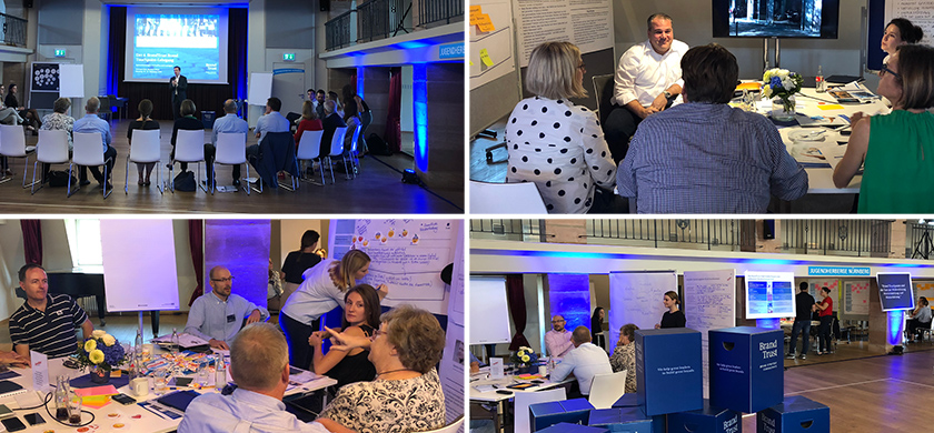 Collage aus vier Fotos, die ein Branding-Workshop oder Event zeigen. Im oberen linken Bild ist eine Präsentation mit einem Vortragenden vor einer Gruppe von Zuhörern zu sehen. Im unteren linken Bild diskutieren Teilnehmer an einem Tisch und arbeiten mit Materialien wie Post-its. Das obere rechte Bild zeigt eine Gruppe von Personen, die an einer Tafel arbeiten. Das untere rechte Bild zeigt eine Gruppe von Teilnehmern, die um einen Tisch mit kreativen Materialien versammelt sind. Im Hintergrund sind Banner und Bildschirme mit Branding-Elementen von BrandTrust sichtbar.